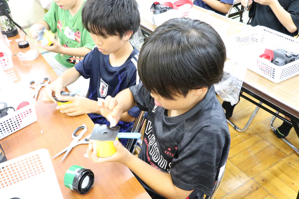 虫眼鏡でカメラのレンズを制作する様子